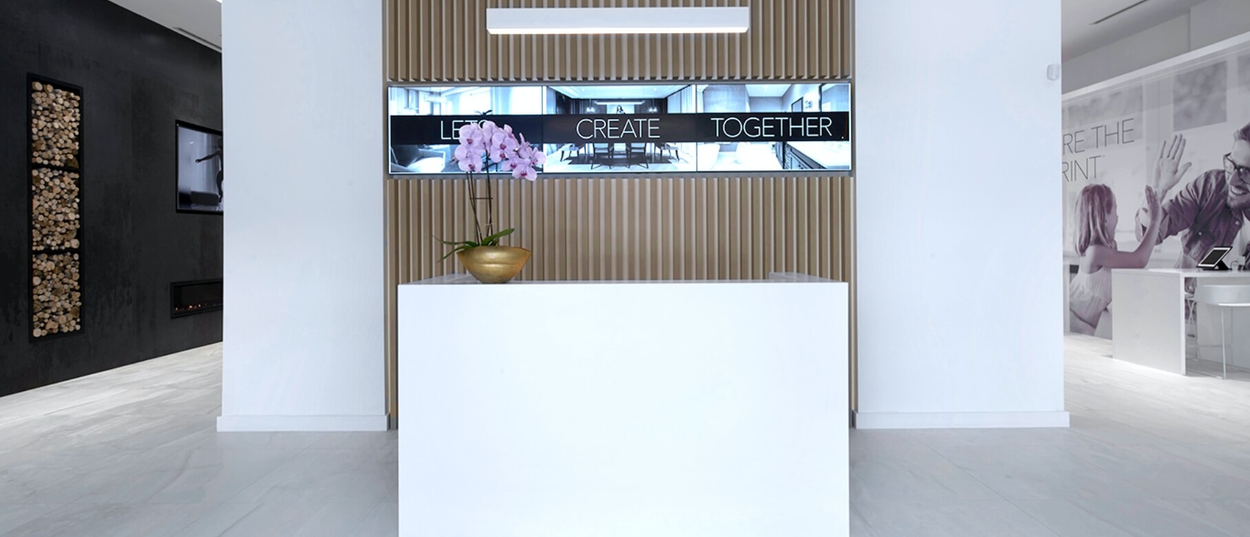 Reception desk at the National Homes Design Studio in Concord, with the words Let's Create Together on screens behind it