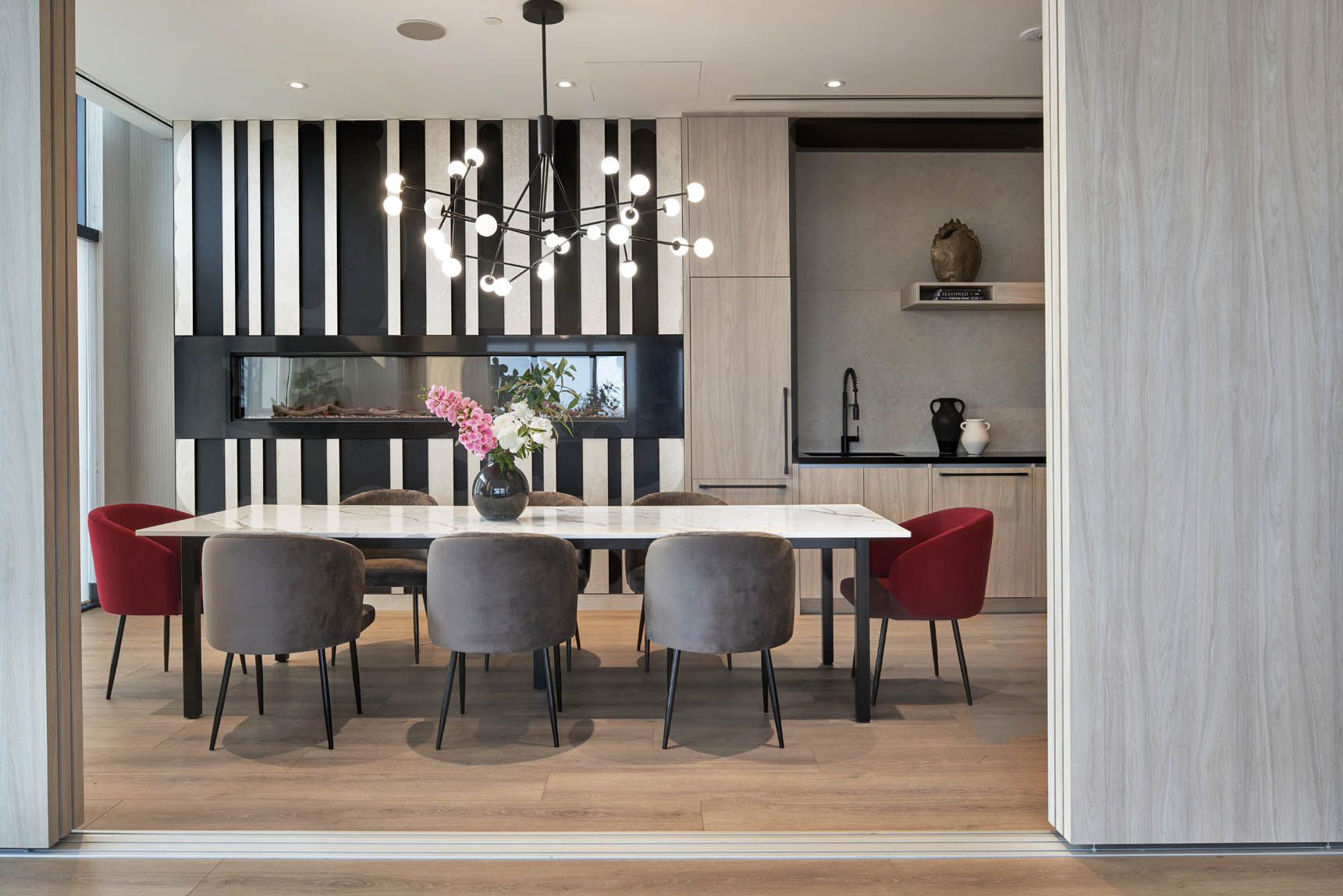 Dining room with a long table, a fireplace wall and a kitchenette at DUO Condos, Brampton